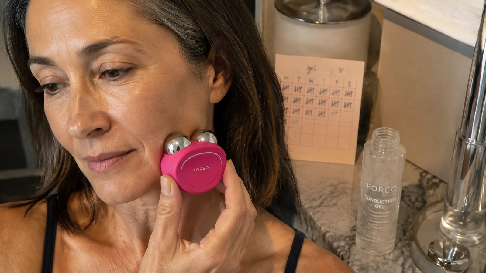 Close-up of a bottle of conductive gel next to the FOREO Bear device, showing how much product gets used per week