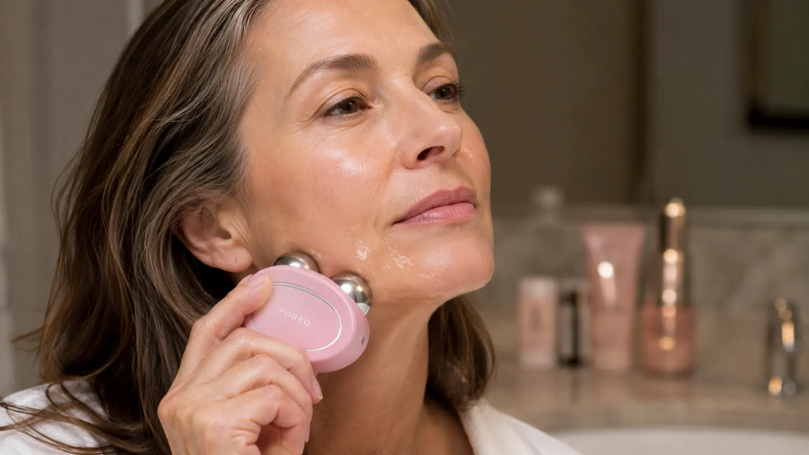 Close-up of a hand holding the FOREO Bear device with conductive gel applied along the jawline